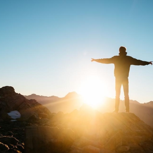SQ man standing on top of mountain with arms outstretched copy