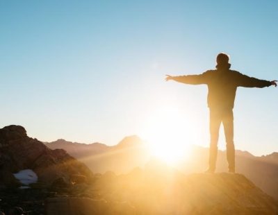 SQ man standing on top of mountain with arms outstretched copy